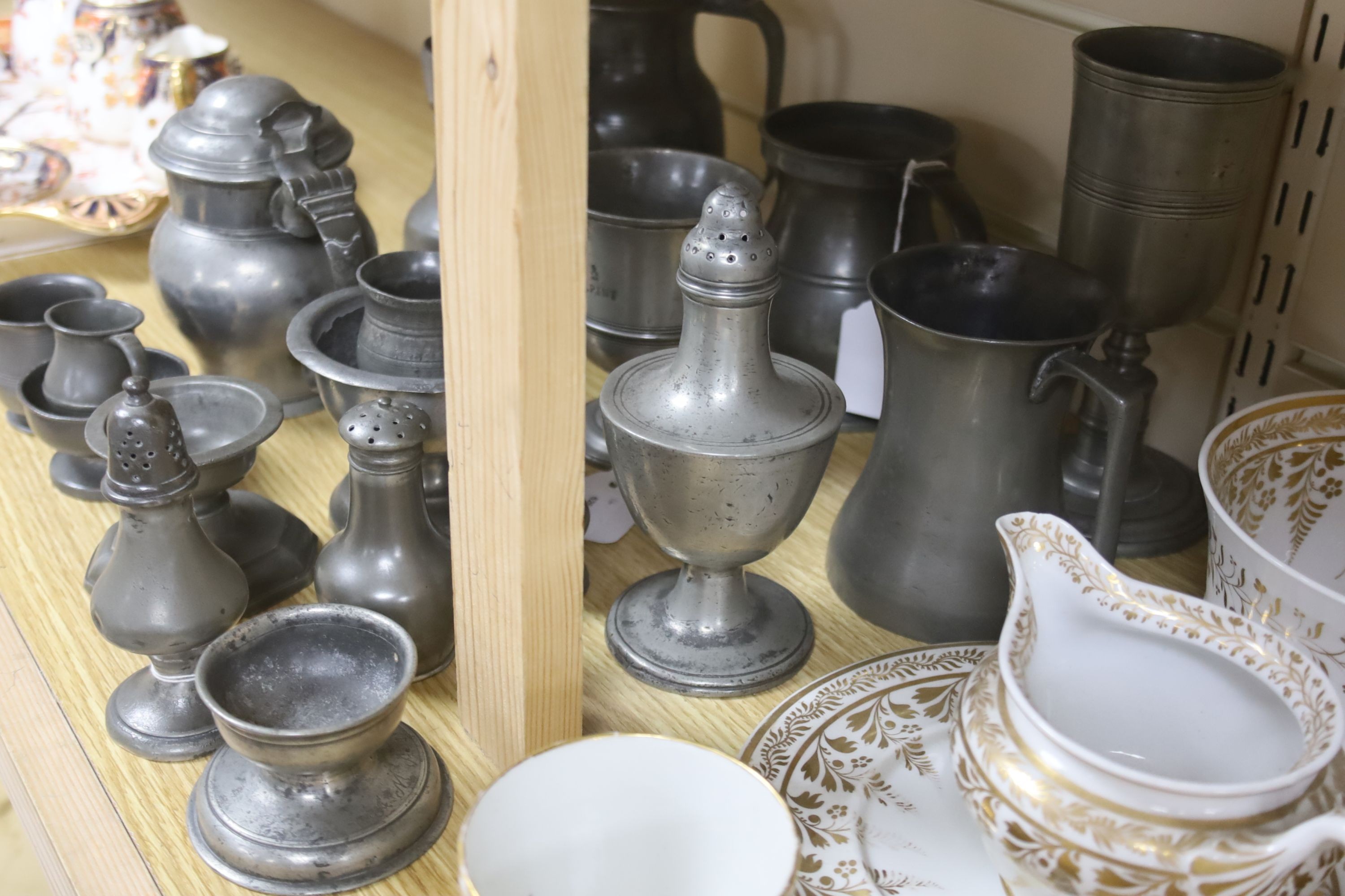 Eighteen items of 18th and 19th century pewter, including lidded jugs, measures, goblets, salt and pepper pots and a chocolate pot